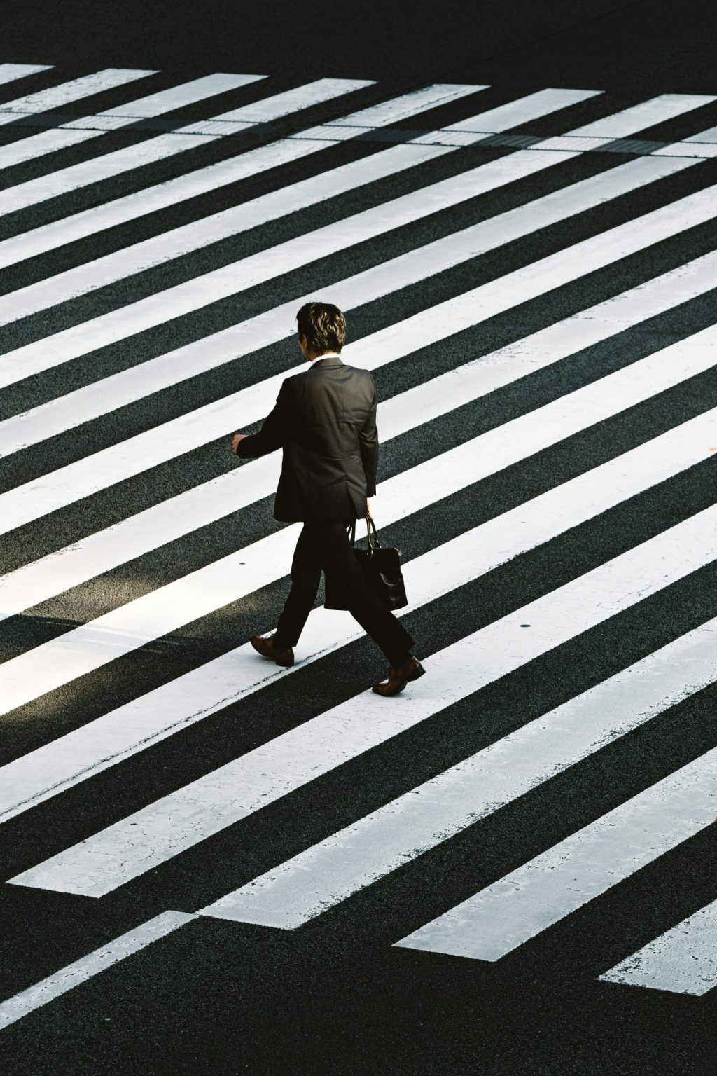 A person in a suit crossing a zebra crossing, seen from above